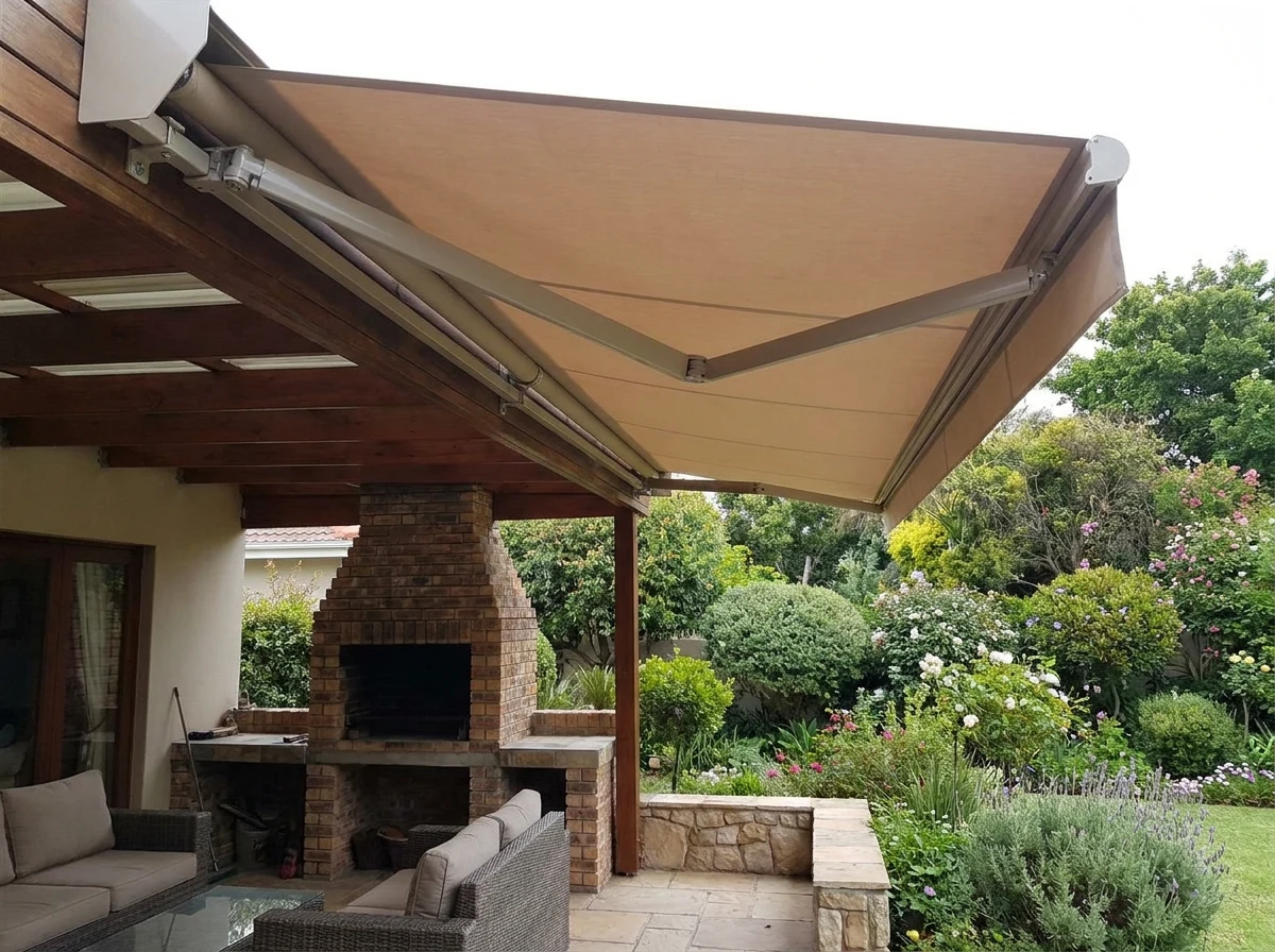 A cream folding-arm awning opened out past a timber pergola over an Illovo patio and its brick braai